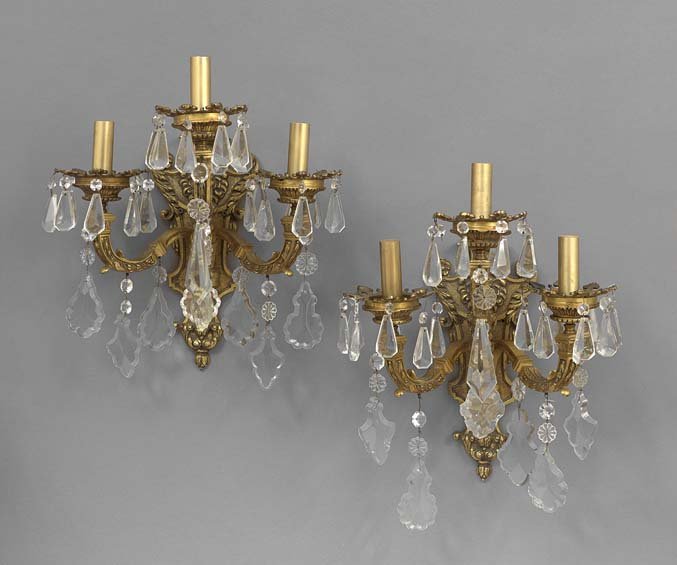 Pair of French Bronze and Crystal Sconces: Pair of French Baroque-Style Bronze and Crystal Three-Light Sconces, the molded backplates with acanthus borders and a broken-arch pediment decorated with a lion's head, the bellflower-molded arms sup