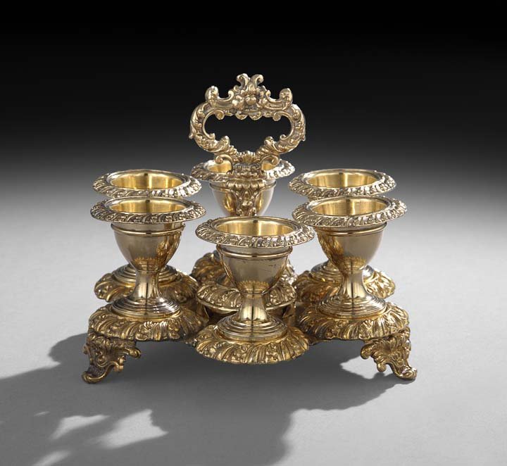William IV Gilt Old Sheffield Plate Egg Cup Frame: William IV Gilt Old Sheffield Plate Egg Cup Frame, second quarter 19th century, of lobed hexagonal form, with a central baluster standard with ring handle finial, raised on three acanthus-scroll feet