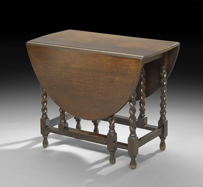 English Oak Drop-Leaf Table: English Oak Drop-Leaf Table, early 20th century, the top with rounded ends and two deep ovoid leaves, raised on a gate-leg support of barley-twist legs joined by a box stretcher and ending in bulb fee