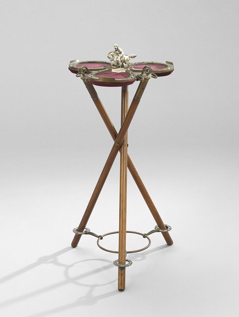 Occasional Table of Equestrian Inspiration: Edwardian Tripodal Occasional Table of Equestrian Inspiration, early 20th century, the upholstered top with horse shoes as a gallery, on crossed supports modeled as riding crops, h. 24", w. 15", d. 15