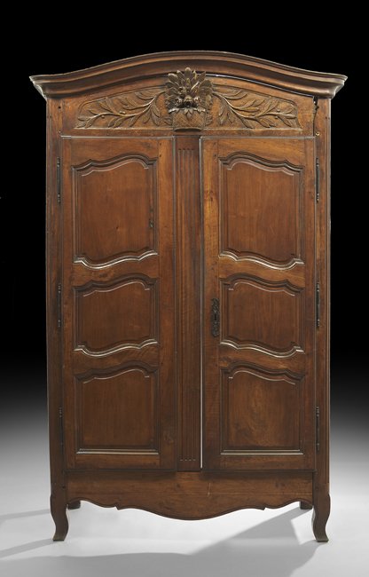French Provincial Fruitwood Armoire: French Provincial Fruitwood Armoire, mid-19th century, the domed and molded cornice above a case fitted with a floral basket and garland-carved frieze over two tri-paneled doors, raised on shaped legs