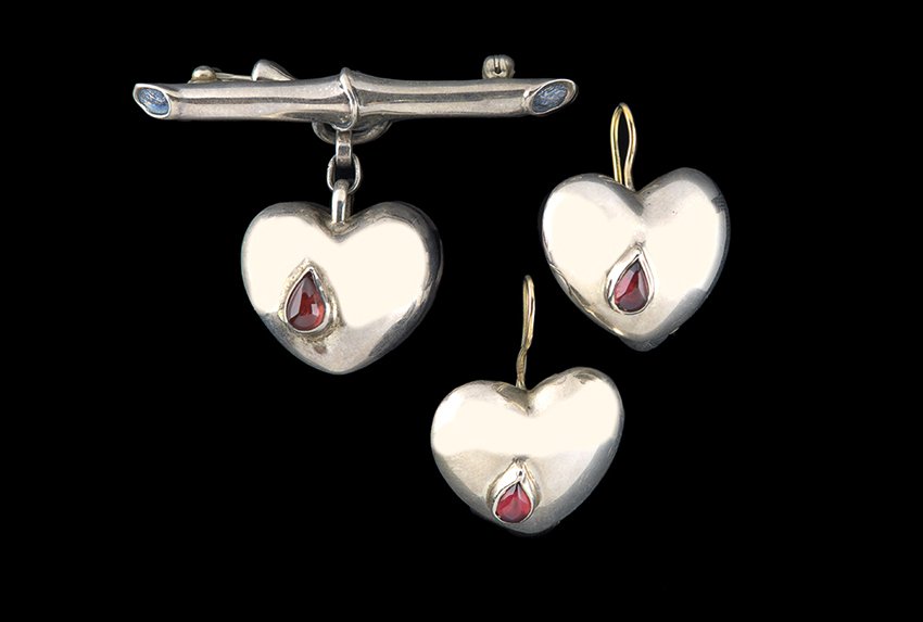 Sterling Silver and Garnet Earrings and Brooch: Pair of Sterling Silver and Garnet "Mignon Faget" Earrings and Matching Brooch, each heart-shaped earring set with a teardrop garnet cabochon, together with a matching heart-shaped brooch.