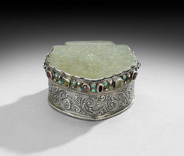 Silver-Mounted Mughal Jade Box: Silver-Mounted Mughal Jade Box, 18th century, the mounting probably Persian, of shield form, the lid inset with a floral-incised jade plaque framed by collet-set turquoise and green and red gems, the 