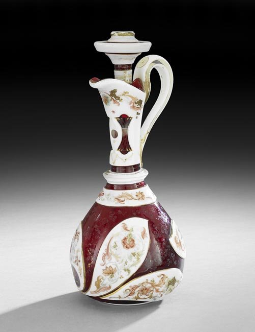Bohemian Enameled Overlay Glass Claret Jug: Bohemian Enameled Overlay Glass Claret Jug, fourth quarter 19th century, the opaline panel decorated with scrollwork overlay, the ruby body decorated with gilt trim, h. 13-1/4", dia. 5-1/4".