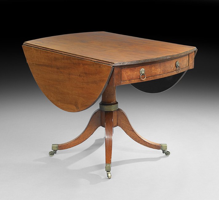 Regency Mahogany Drop-Leaf Library Table: Regency Mahogany Drop-Leaf Library Table, first quarter 19th century, the top with rounded and reeded ends and like ovoid drop leaves, above a conforming frieze fitted with a drawer to either end, rai