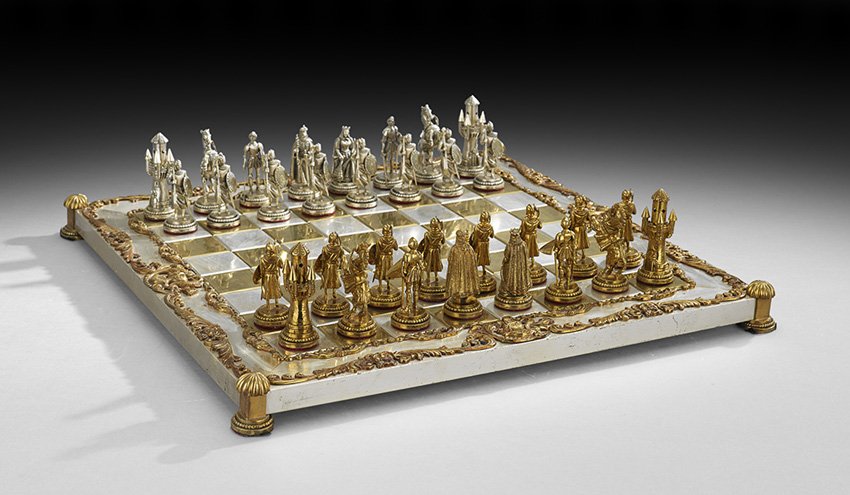 Renaissance-Style Brass and Steel Chess Set: Renaissance-Style Lacquered Brass and Steel Chess Set, mid-20th century, both board and pieces signed "F.M.G.", the board resting on reeded feet, the edges decorated with armor helmets framed in raise