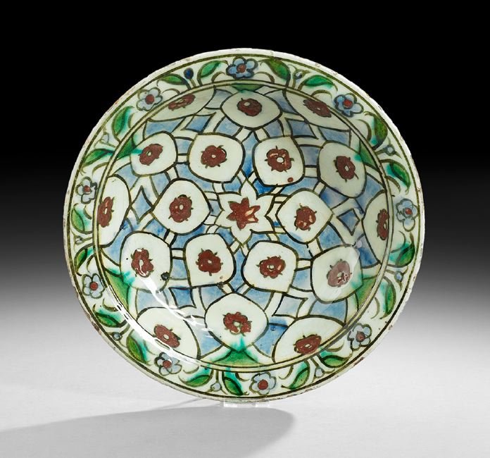 Middle Eastern Iznik-Style Glazed Pottery Bowl: Iznik-Style Glazed Pottery Bowl of Middle Eastern Origin, decorated with a grid of red flowers in stylized panels on a blue ground, finished with a floral border, h. 2-3/4", dia. 11-3/4".