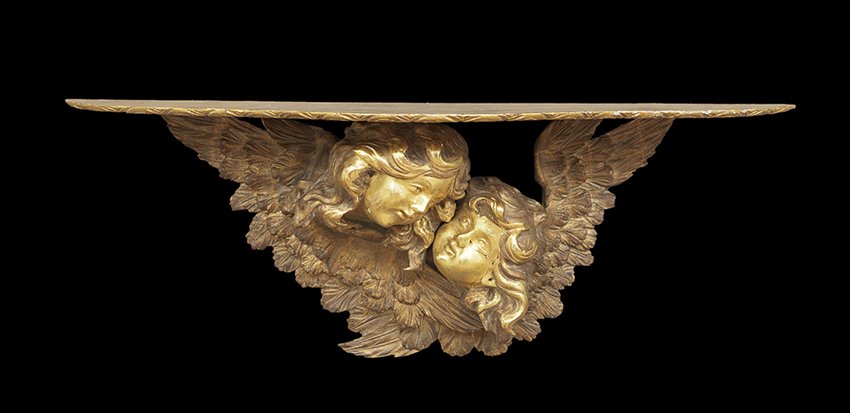Unusual Carved Giltwood Bracket: Unusual Carved Giltwood Bracket ca. 1900, decorated with a pair of angel's heads against outstretched wings holding a serpentine shelf with a leaf-carved edge, h. 15-1/2", w. 42-1/2", d. 11-1/2".
