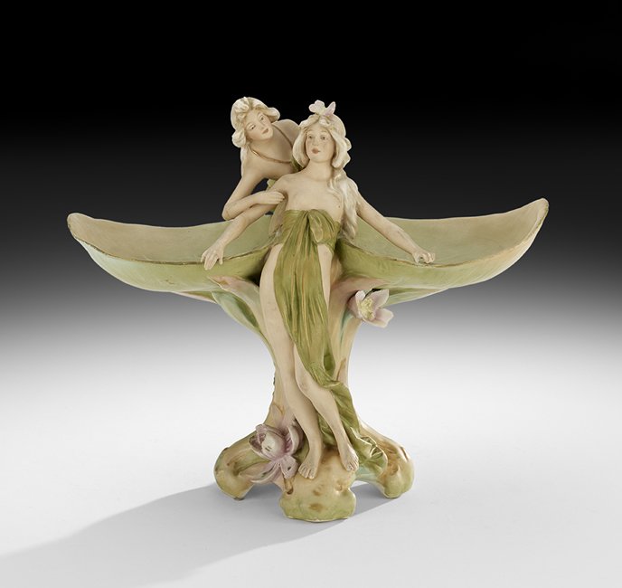 Royal Dux Porcelain Art Nouveau Centerpiece: Royal Dux Porcelain Art Nouveau Centerpiece, ca. 1900, in the form of two water nymphs with water lily leaves and blossoms, marked with a pink biscuit "E" triangle mark, h. 13-1/4", w. 16", d. 7-1/2".
