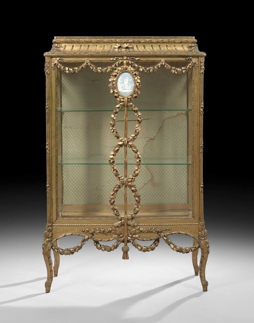 Napoleon III Giltwood Vitrine: Napoleon III Giltwood Vitrine, third quarter 19th century, the stepped cornice dentillated and above a case fitted with a glazed front and two side glazed doors, the front with an applied floral garla