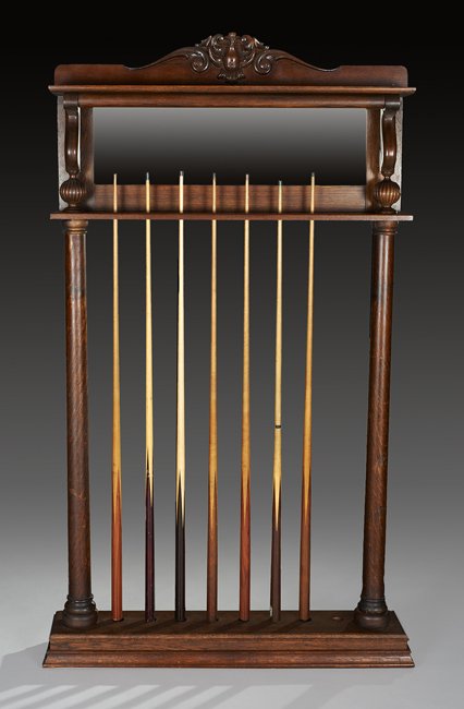 Oak Billiard Cue Rack and Cues: Oak Billiard Cue Rack and Cues, ca. 1900, the rack supported between two turned columns, the beveled mirrored top panel headed by a shelf, with slots for eight billiard cues, and including seven cues,