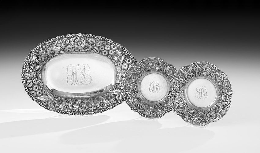 Three Baltimore Sterling Silver Dishes: Three Baltimore Sterling Silver Dishes, first quarter 20th century, by Jenkins & Jenkins, comprising two small wine coasters, dia. 5-7/8", and an oval bread tray, l. 11-1/2", decorated all over with f