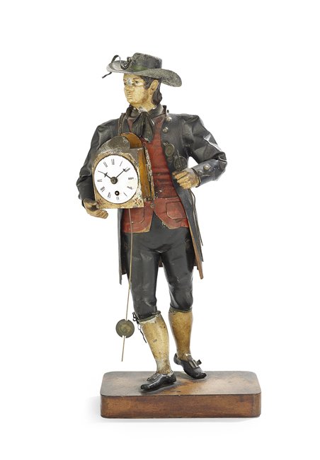 Continental Tole Figural Clock: Continental Tole Figural Clock, 19th century, on a wooden base, the painted tole figure of a man modeled carrying a functioning wag-on-the wall clock in one hand and extra pendulums in the other, and