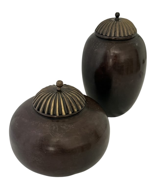 MAITLAND SMITH BRONZE VASES JAR SET: Two bronze jars with lids. The vessels feature a turned wood body with a dark, polished finishes that display visible wood grain patterns, particularly on the base. They are topped with a heavy cast m
