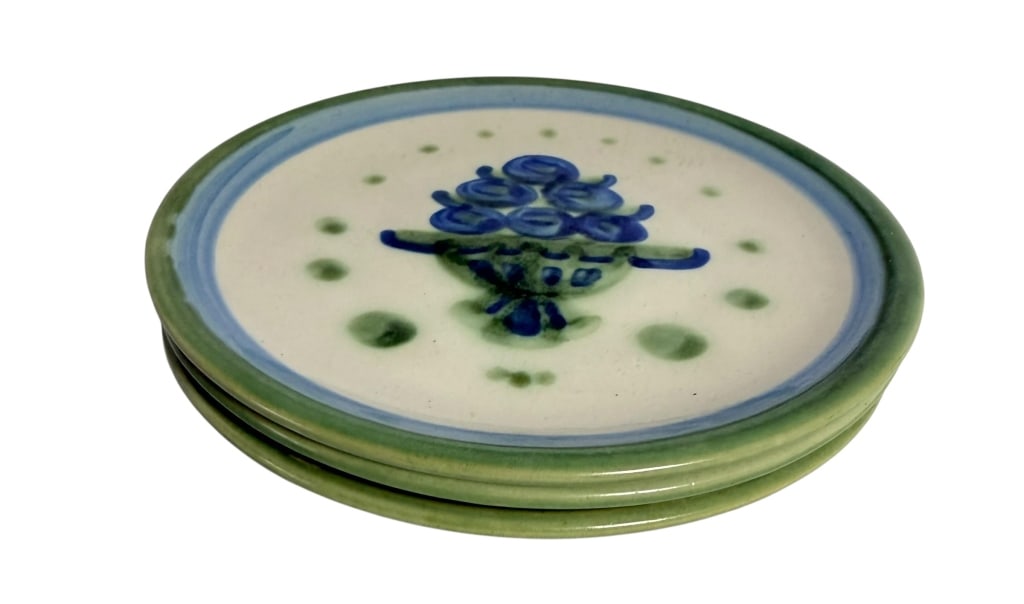 3 SIGNED HAND-PAINTED STUDIO POTTERY FLORAL PLATES: Charming set of three hand-painted ceramic plates, each featuring a stylized blue floral arrangement within a decorative basket or urn. The cream-colored ground is accented by soft blue concentric bor