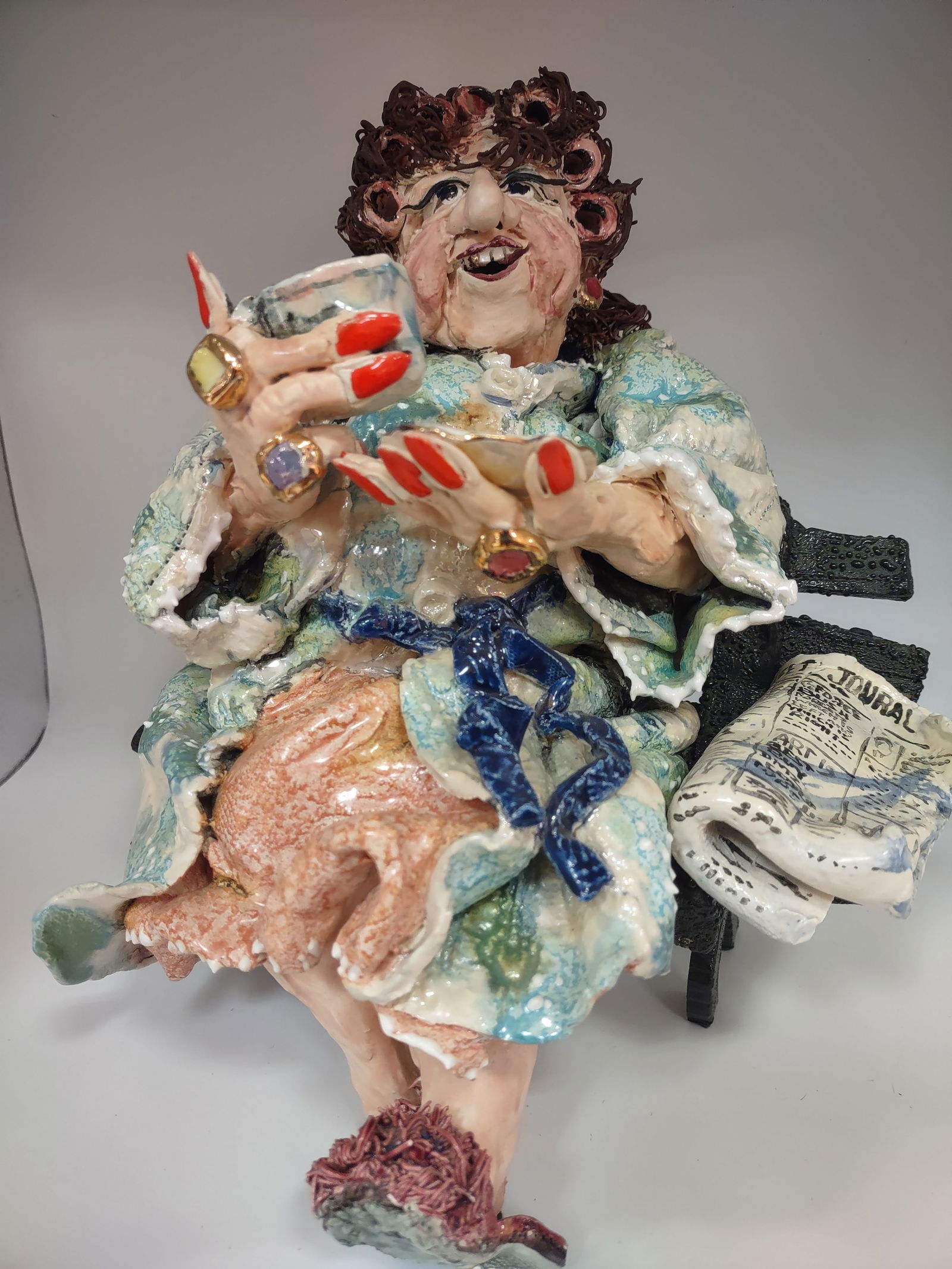 Original Clay Scuipture by "D.M.Z. Coyle": DMZ Coyle clay folk art sculpture depicting an eccentric woman enjoying a cup of coffee on her favorite spot after reading her newspaper. Numbered to underside. Measures 8" x 8" x 10.5" H in excellent