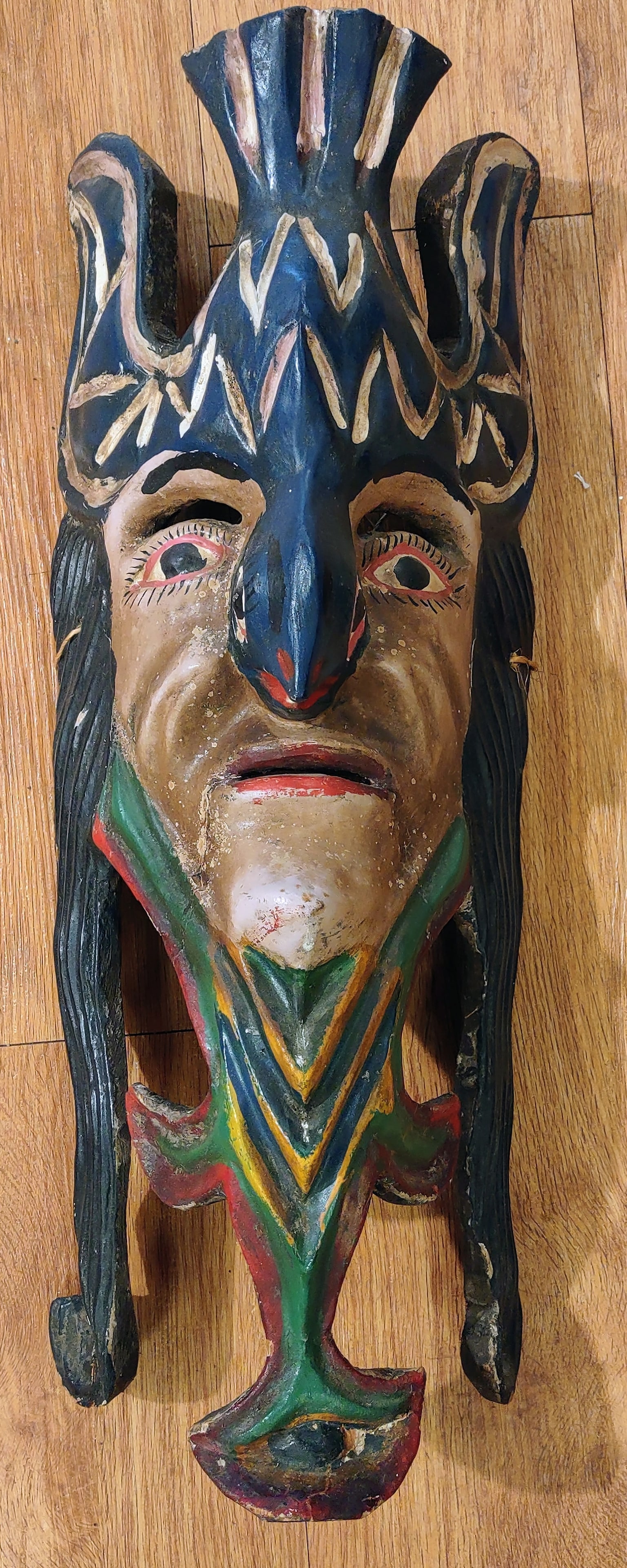 Antique Mexican Mask: A striking Antique hand-carved wooden Mexican mask featuring a dramatic elongated face with expressive eyes, a prominent nose, and a stylized crown-like headdress. The mask is decorated with bold