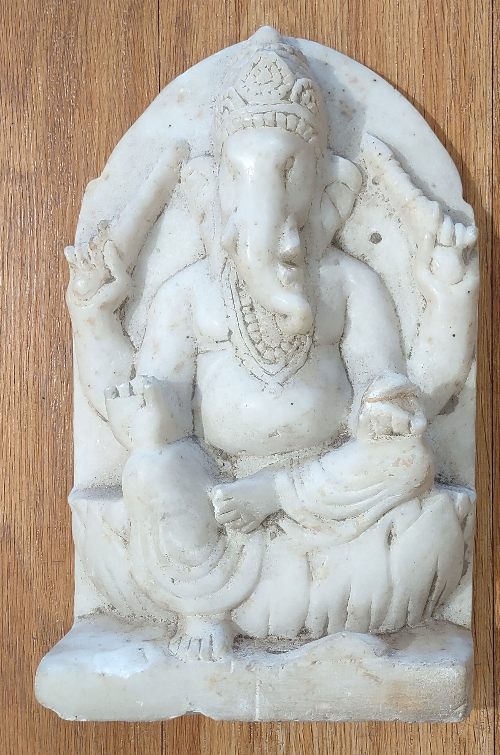 Marble Stone Ganeha 1800 's: Seated in a traditional pose beneath an arched niche, the deity is rendered with characteristic attributes and stylized detailing. Likely carved in marble or alabaster, with a soft, pale tone and