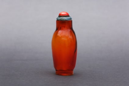 A SLENDER BALUSTER TRANSPARENT AMBER GLASS BOTTLE