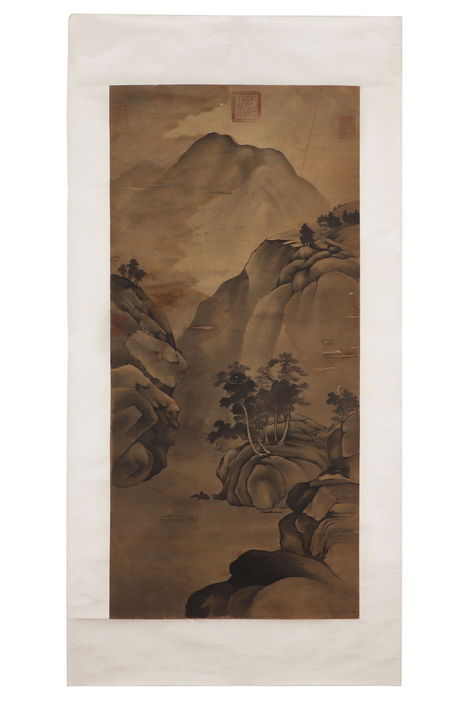 A Chinese Landscape Painting: A Chinese landscape painting with no signature, featuring four seals. The landscape is depicted in ink on silk. Mounted in the form of mirror centers. H: 94cm W: 44cm (painting)