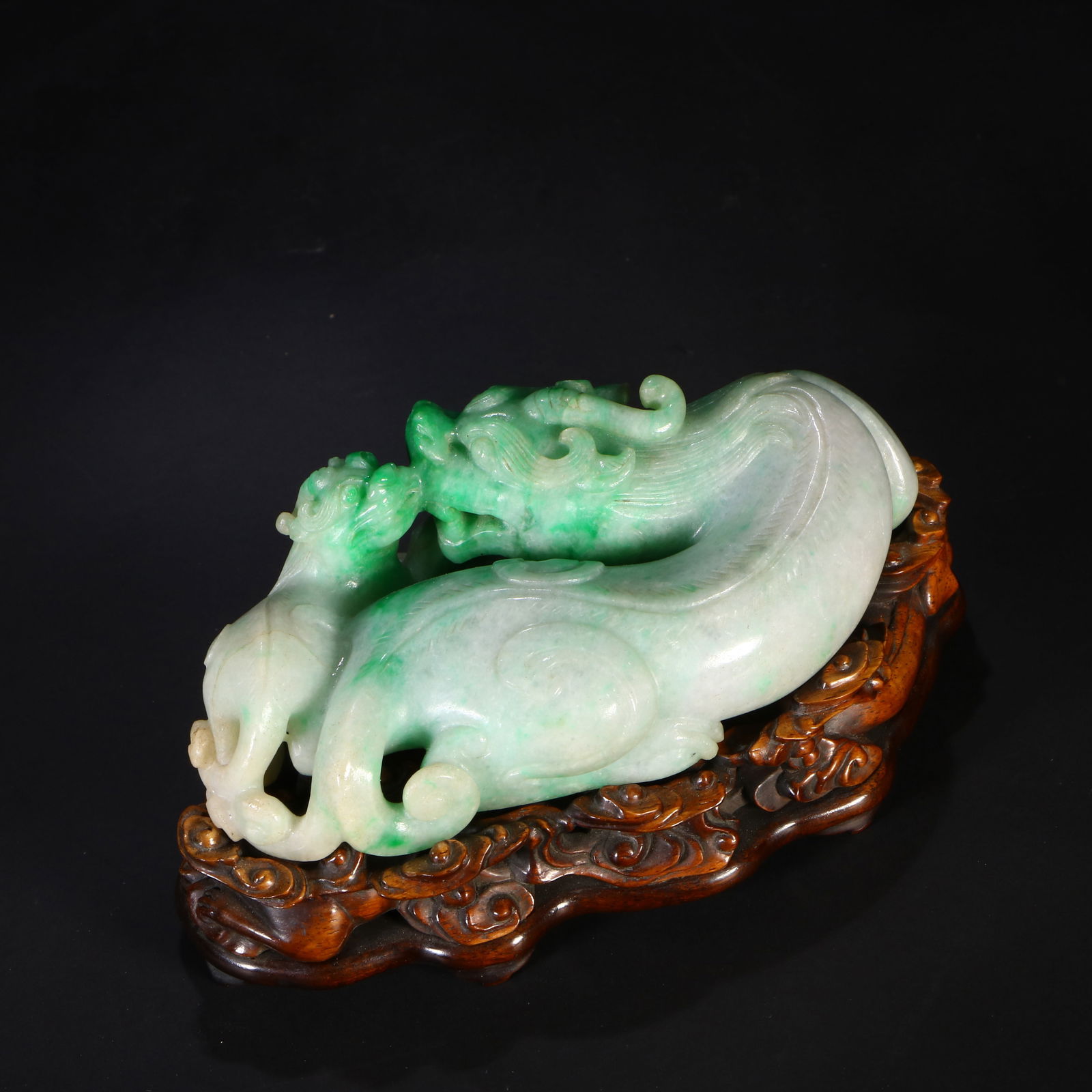 A jade auspicious beast ornament: A jade carving. It features two mythical beasts and comes with a wooden base.H:5.8 cm W:11.8 cm