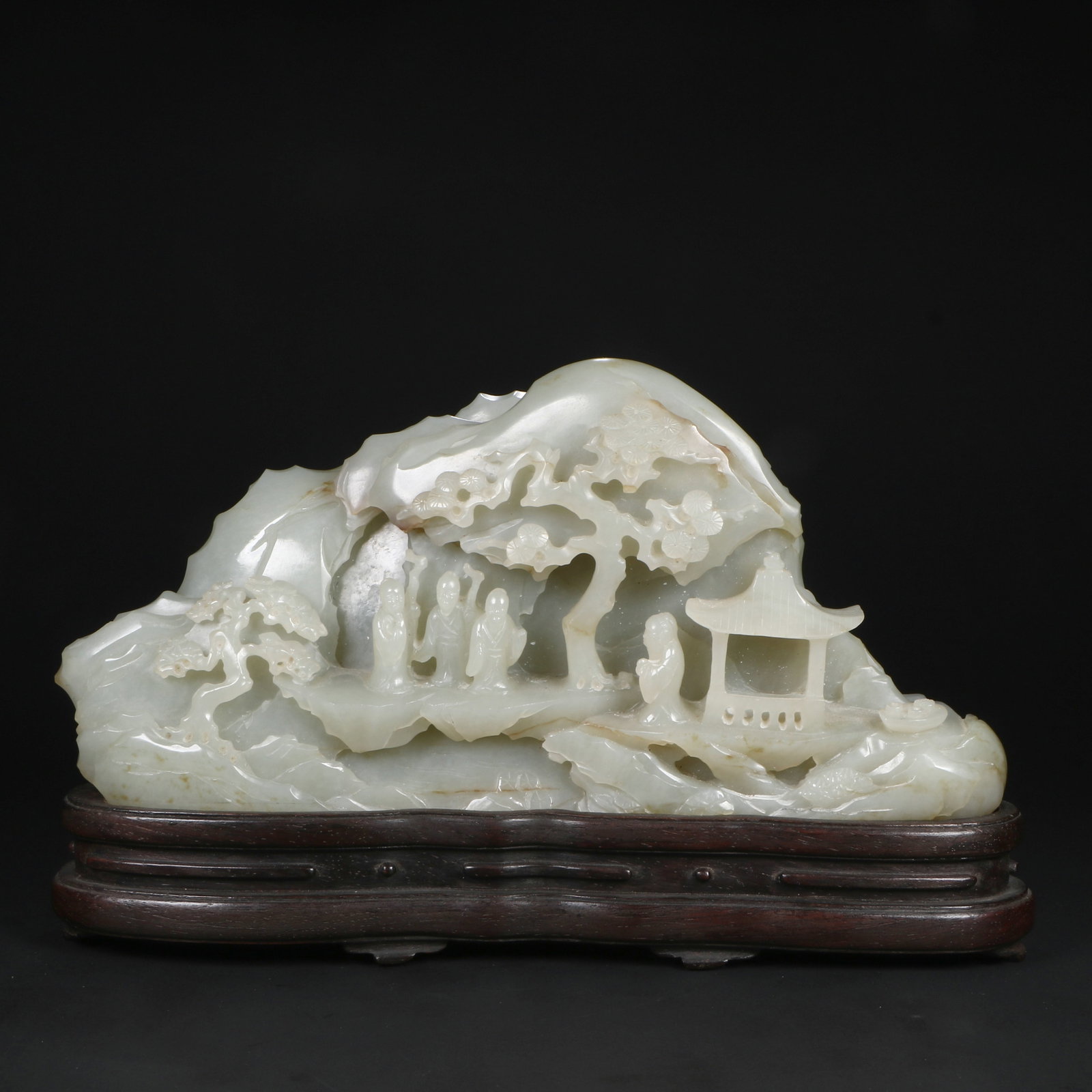 A Hetian jade ornament: The jade is carved into figures playing on the mountain, with a suitable wooden base, total height 13.5cm, net height 10.5cm, length 21.5cm, width 5cm.