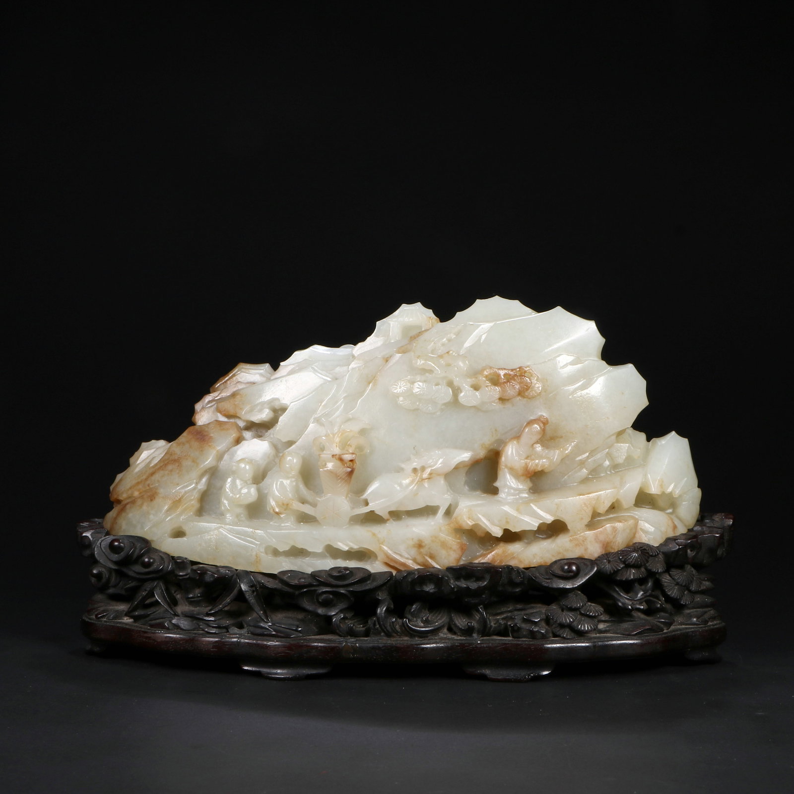 A Qing Dynasty Hetian jade ornament: Part of the jade is carved into the shape of a mountain, with a suitable wooden base at the bottom. Total height 10cm, net height 6.5cm, length 16cm, width 4.5cm.