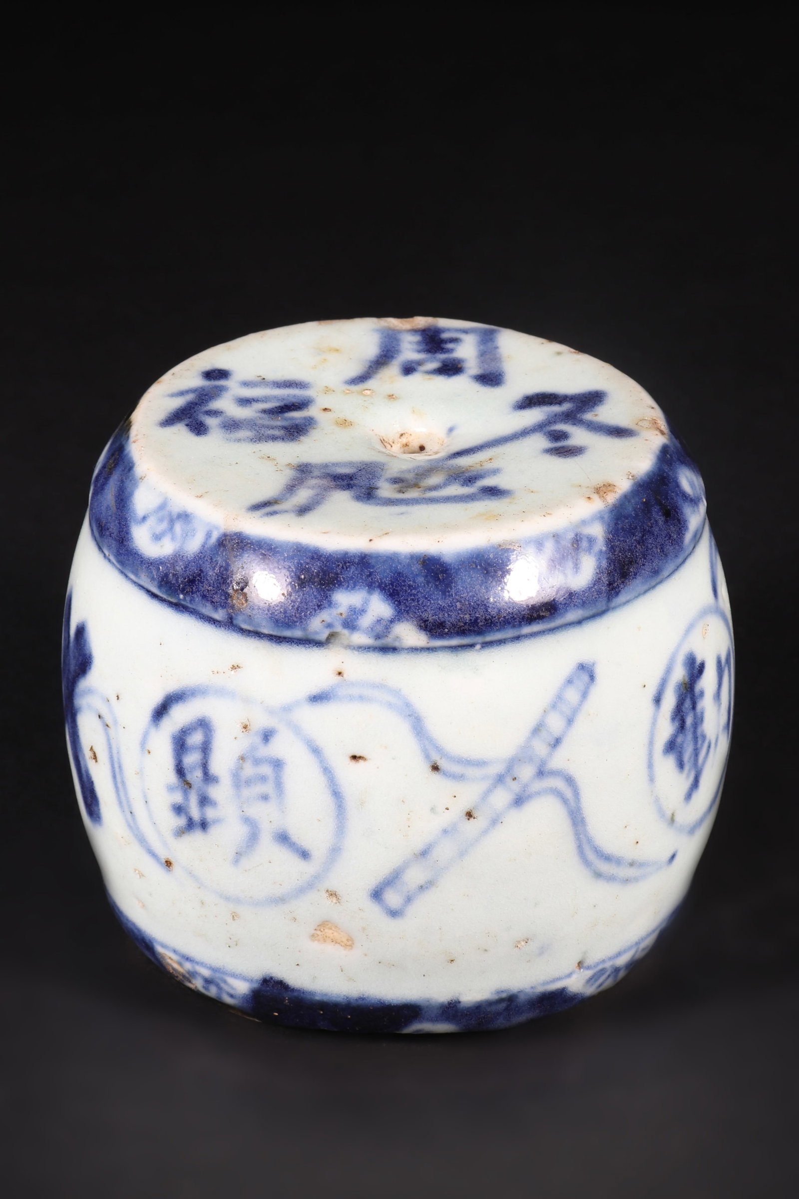 A Blue and White Porcelain Candle Holder: A blue and white porcelain candle holder, with a drum shaped design and text and patterns on it. H: 6.5cm D: 7.5cm (Max)