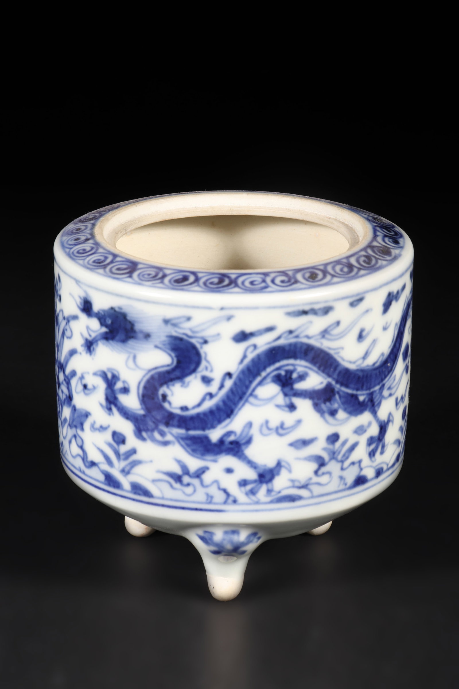 A Blue and White Porcelain Incense Burner: A blue and white porcelain incense burner with dragon and flower patterns on its body and three legs. H: 8cm D: 8.5cm (Max)