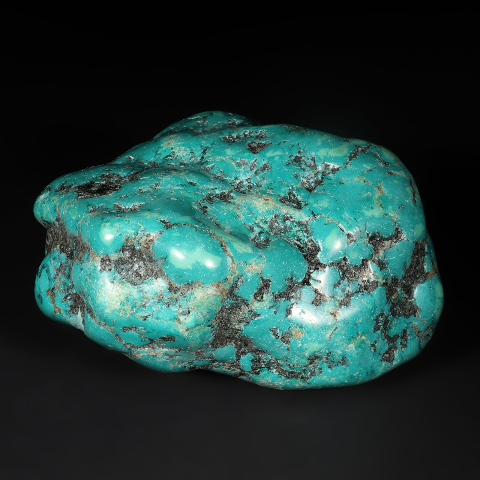 A Turquoise: A turquoise with irregular shape and some black texture. H: 12cm L: 12cm W: 6cm (Max)