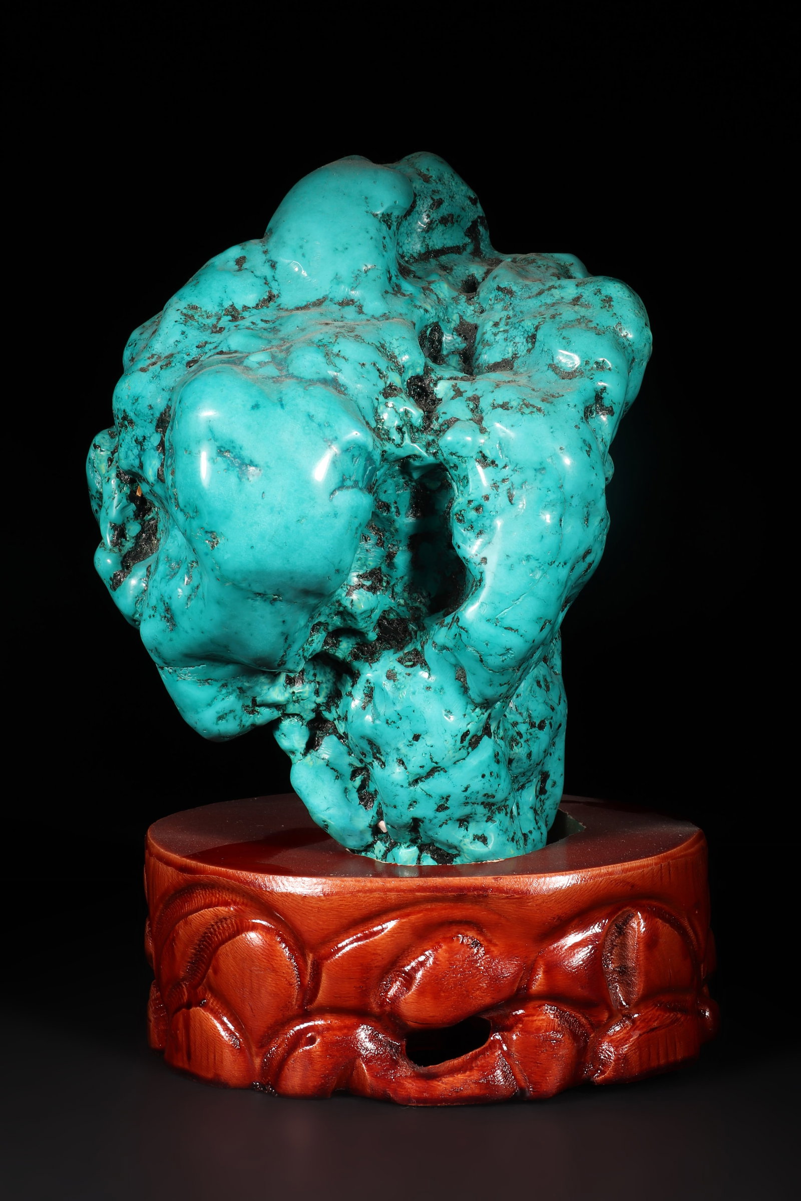 A Turquoise Ornament: A turquoise ornament with irregular shape and some black texture. Comes with a wooden base. Overall H: 23.5cm L: 14cm W: 14cm (Max)