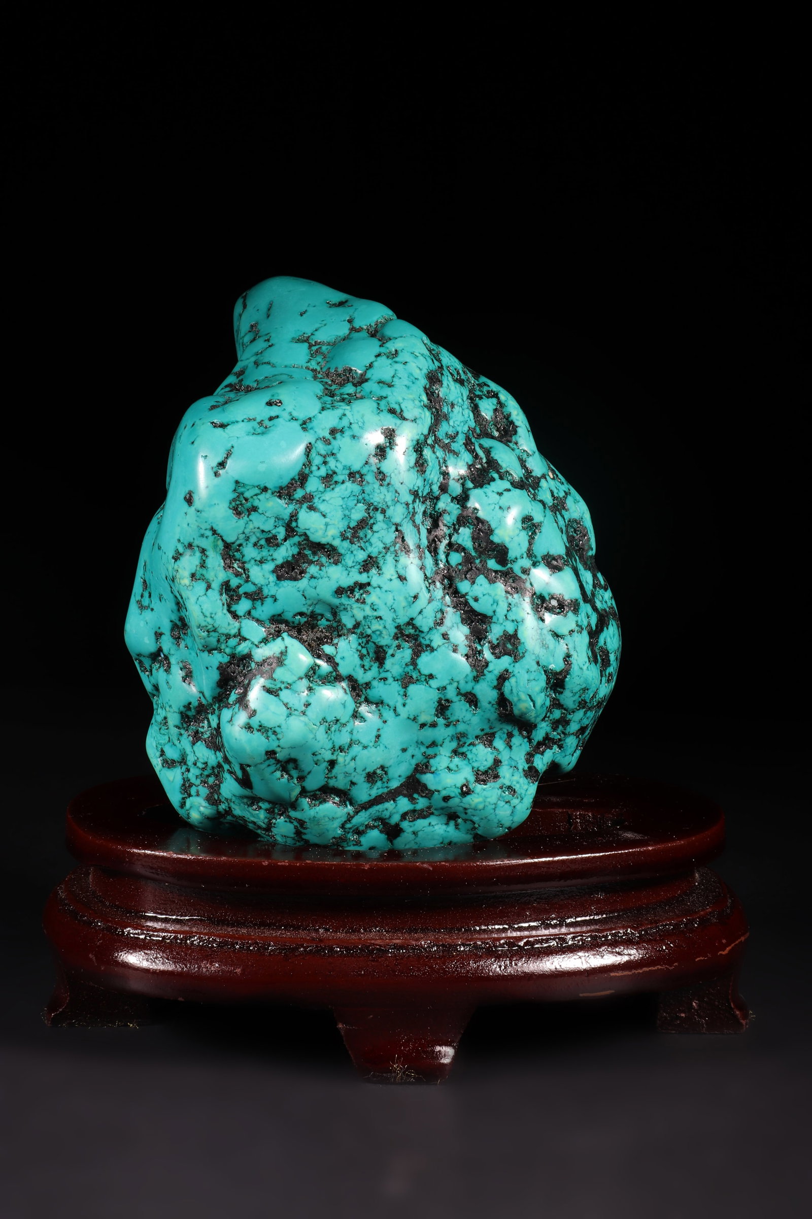 A Turquoise Ornament: A turquoise ornament with irregular shape and some black texture. Equipped with a detachable wooden base. Overall H: 14.5cm, Turquoise H: 11.5cm L: 9.5cm W: 7.5cm (Max)