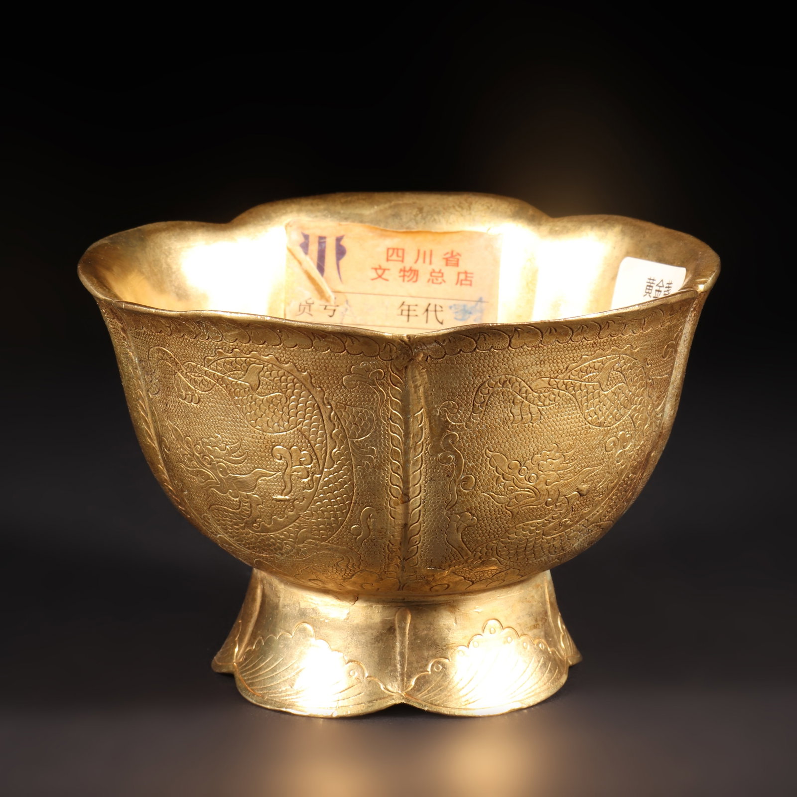 A Gilded Bowl With The Words' Tang Dynasty Zhenguan ': A gilded bowl with a five petal flower shaped mouth and a lotus shaped base. The bowl wall is engraved with patterns of dragons and petals, and the bottom of the bowl is engraved with the words "Tang