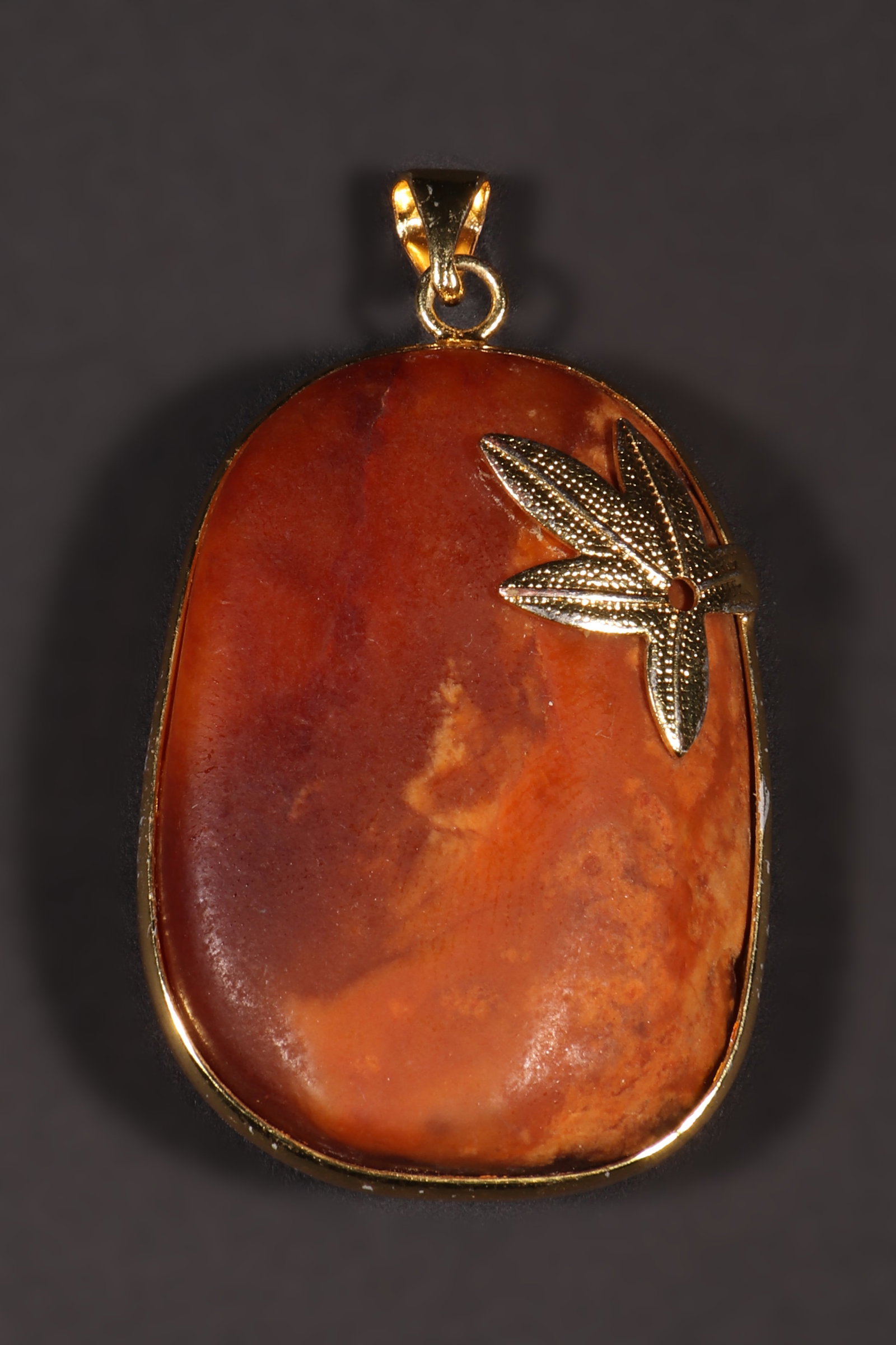 A Hotan Jade Pendant: A Hotan Jade pendant. There are metal frames and floral decorations. H: 3.5cm L: 2.7cm W: 0.8cm (Max)