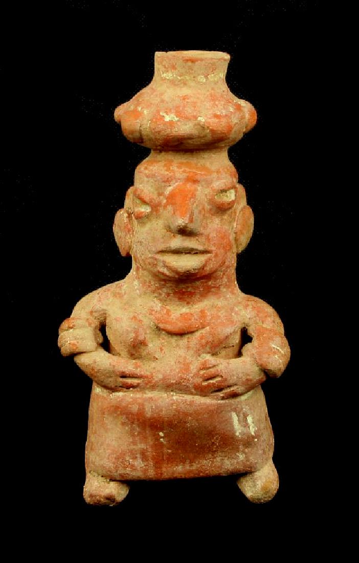 6" Pre-Columbian Nayarit Terra Cotta Figurine: Extra fine redware example (with great orangish hue) from Mexico. Some remnant white paint. All there and stylized with lobed pot balanced on her head, with arm bands, dress, and expressive faci