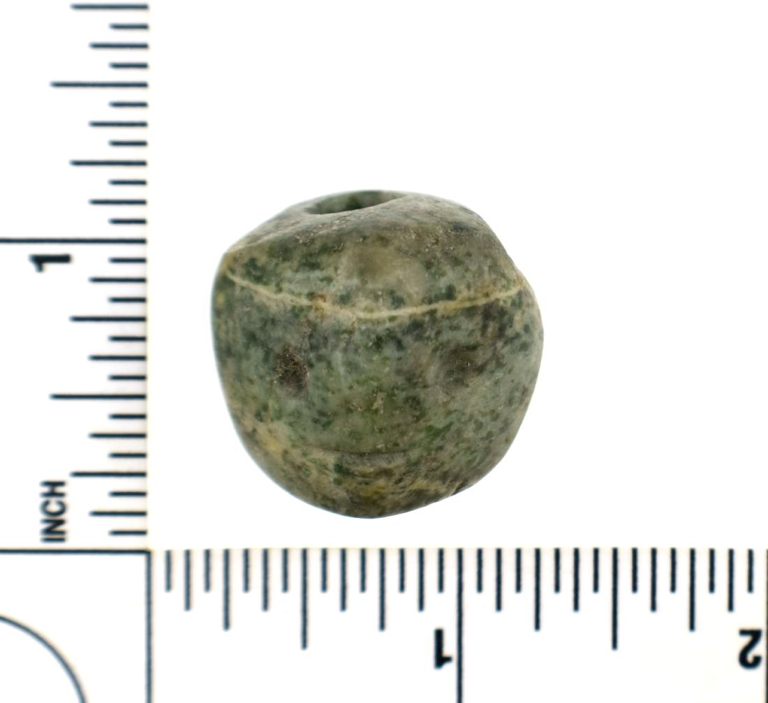 Exceptionally Fine Mayan Face Effigy Bead: Pre-Columbian Mayan Culture, ca. 600-900 A.D. Greenstone. Biconically drilled for suspension at the top and back of the head. Distinct concentric facial features including eyes and mouth and a natural