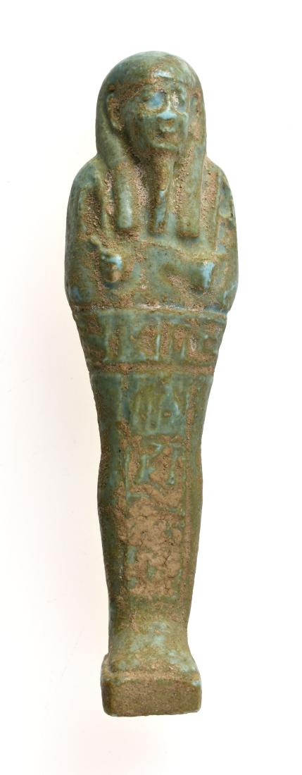 Excellent 107mm Egyptian Turquoise Glazed Ushabti: Egypt. ca. 664-332 B.C. Mummiform figure wearing a tripartide wig, carrying crook and flail. The front has one line of horizontal and one long vertical column of hieroglyphs. It exhibits original calc