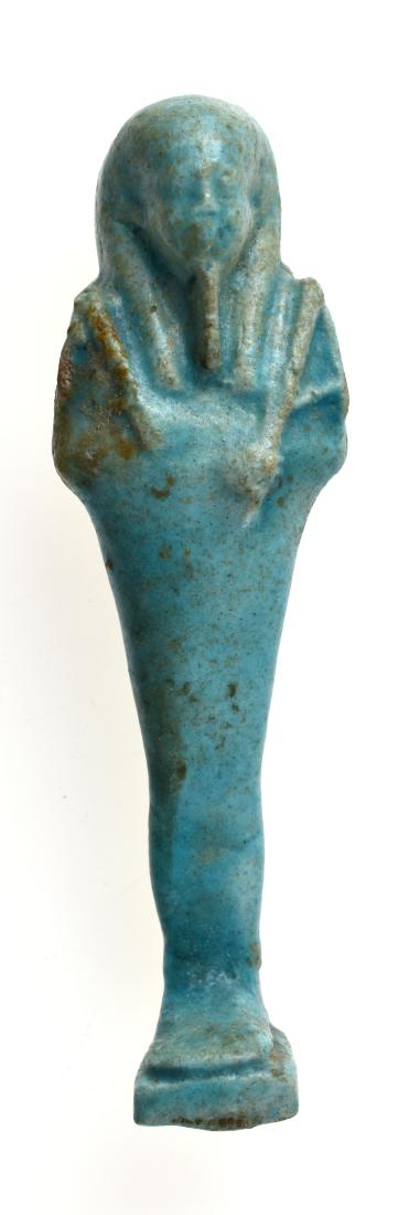 Vibrant Blue 102mm Egyptian Faience Ushabti: A vibrant blue Egyptian faience Ushabti. Late Period, 30th Dynasty - Ptolemaic. ca. 380 - 30 B.C. Mummiform wearing tripartite wig and false beard, arms folded across chest, hands holding a pick and h