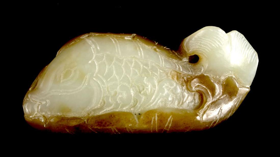 EXQUISITE CHINESE QING DYNASTY JADE FISH TOGGLE: Classic form masterfully auspiciously carved with left facing three dimensional Fish in light celadon with the base and back in a slightly darker green/brown two-tone Nephrite Jade pebble. Detailed ca
