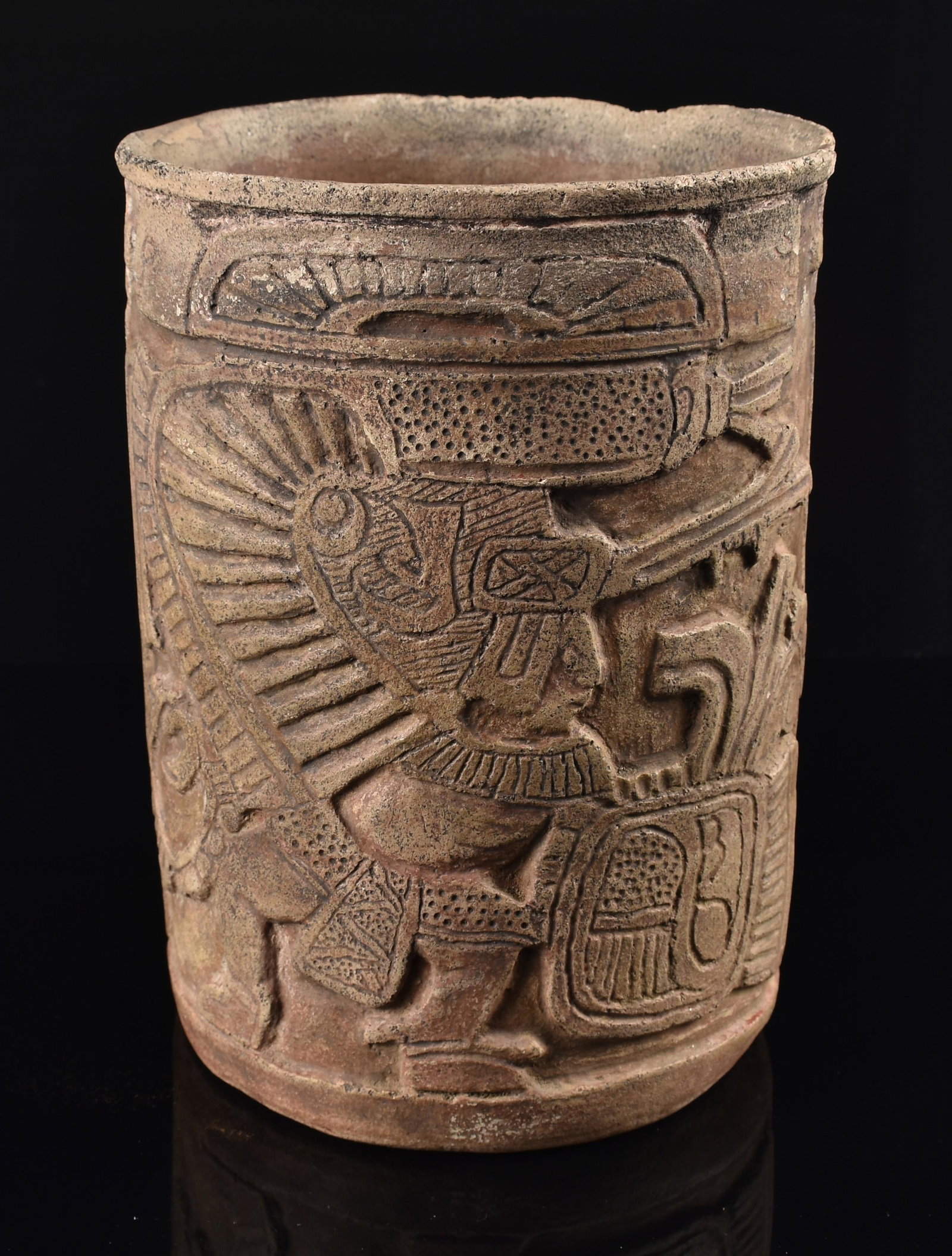 7-5/8"Pre Columbian Carved Classic Mayan Vase: An important Pre Columbian carved Mayan Vase of a standing warrior holding a shield and wearing an elaborate headdress. Glyphs and iconographic elements are carved throughout the vessel in