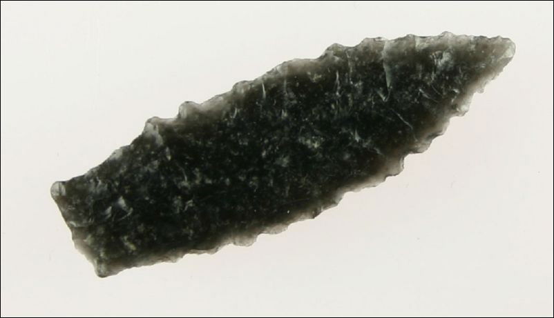 1 1/2" Perfect Humboldt Variant: Nicely translucent Obsidian and perfectly crafted. Distinct stem and heavily serrated edges. Would have been a lethal atl-atl dart. Found in Lake Co., Oregon. Ex- Kirkpatrick Collection.