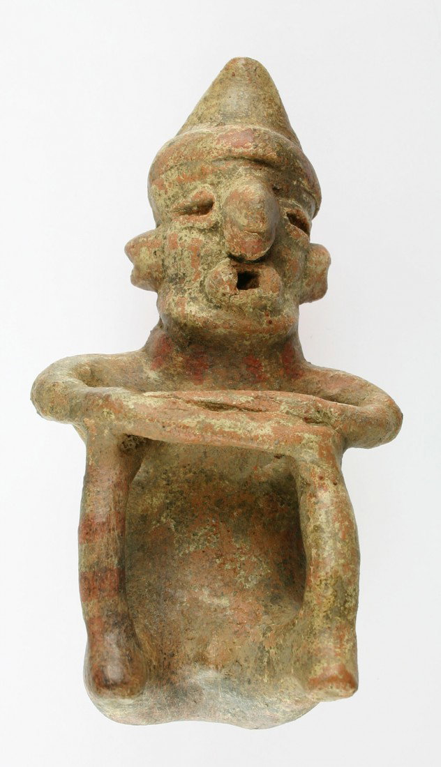 5 3/4" Nayarit Seated Figurine: Completely intact with paint remnants. Expressive form with nose ring, hat, folded arms, and genitalia. Arms and legs are constructed separately and apart from the figurine which is complex for the ty