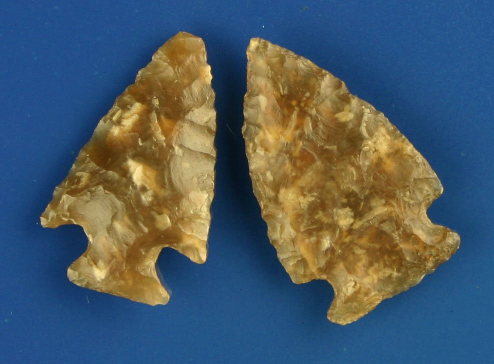Great Pair of Translucent Knife River Darts: 1 1/4" Besant and a 1 3/16" Galt. Classic root beer colored Knife River flint with great translucency. Plains types. Ex- Lloyd Dugstad Collection, Who's Who Vol. 2, page 59.