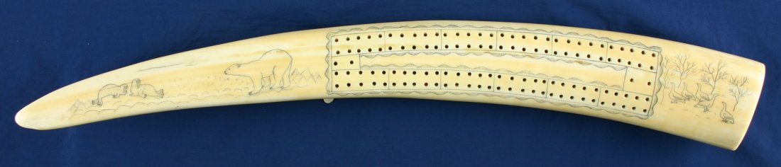 20" Eskimo Cribbage Board: Walrus Tusk (Ivory) example with peg-legs and extensive engraved arctic scenes. Bears, Geese, Seals, Cabin, and Dogsled Team all depicted. Carving not older than 75 years. US Buyers only. No shipments