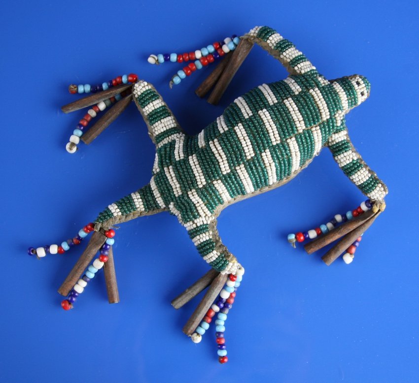Sioux Beaded Fetish: Circa Late 1900's fully beaded umbilical cord lizard fetish with tin cones and beads. Very good condition. Effigy measures 6" X 4" plus cones and beads.