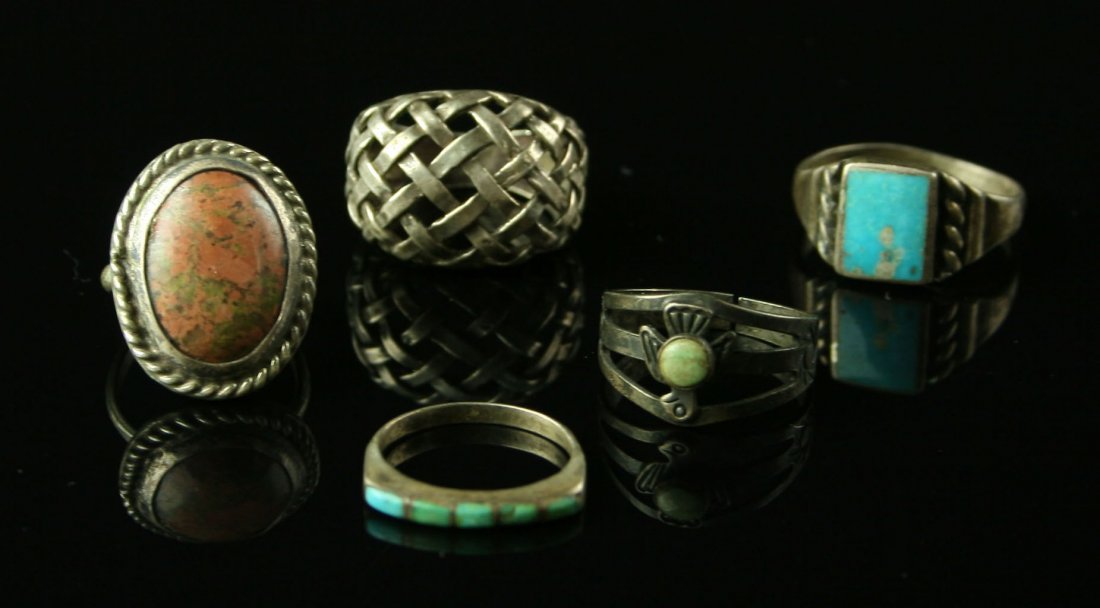 5 Antique Silver Native American Rings: One with Thunderbird marked 'Sterling'. Others no marks. Turquoise, one with lattice work, and one with a pretty colorful cabachon. Glass display frame included.