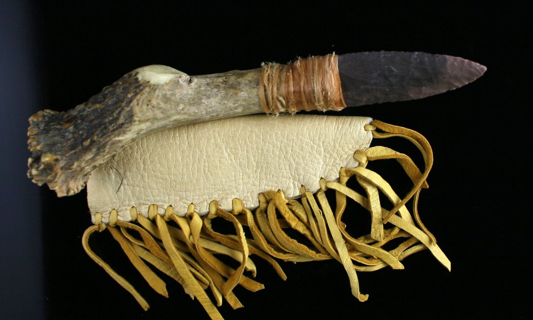 10 3/4" Hafted Flint Blade: Modern reproduction with a soft Hide Sheath with fringe. Well hafted so cannot tell what style of base this flitn blade has.