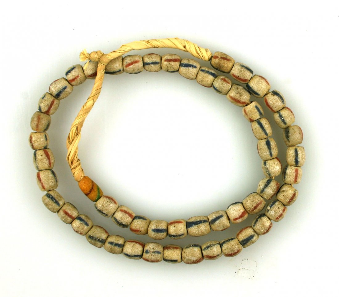 20" String of Sand-Cast Beads: White with red & blue stripes. Strung on grass.