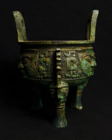 An Archaic Bronze human face three-legged ding