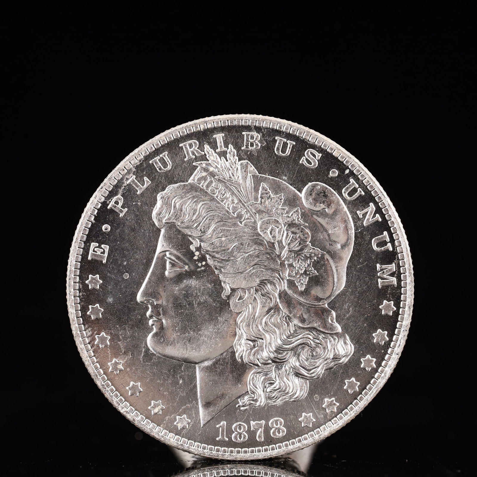 USA Morgan Dollar 1878 Coin: Obv: profile bust with date below and E PLURIBUS UNUM legend and stars around. Rev: eagle with In God we trust above within wreath with UNITED STATES OF AMERICA ONE DOLLAR legend. IN GOD WE TRUST / LI